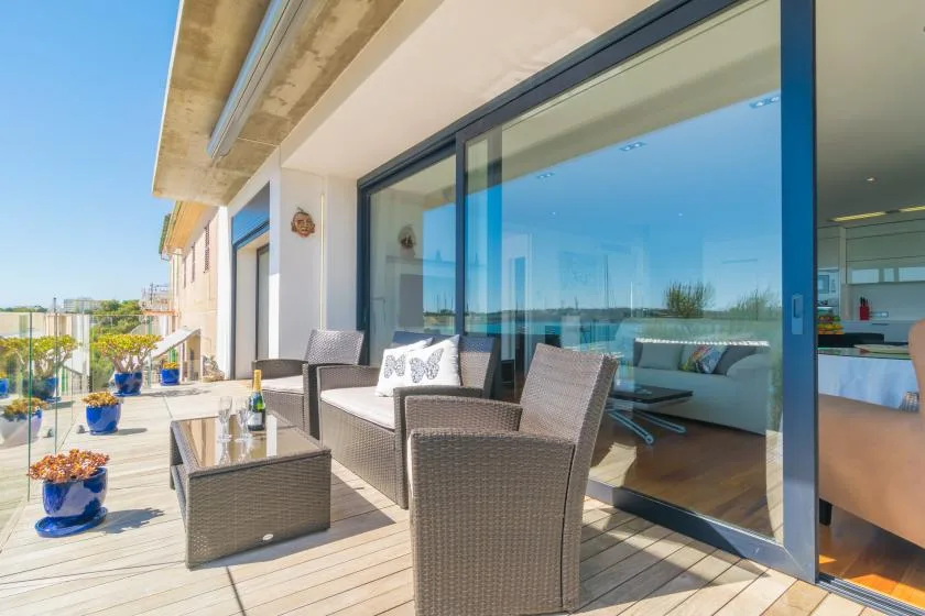 A balcony seating area with woven outdoor furniture beside large glass doors.