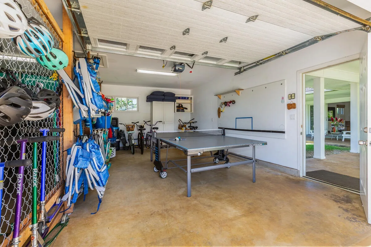 Un área recreativa en un garaje con una mesa de ping-pong y equipo deportivo.