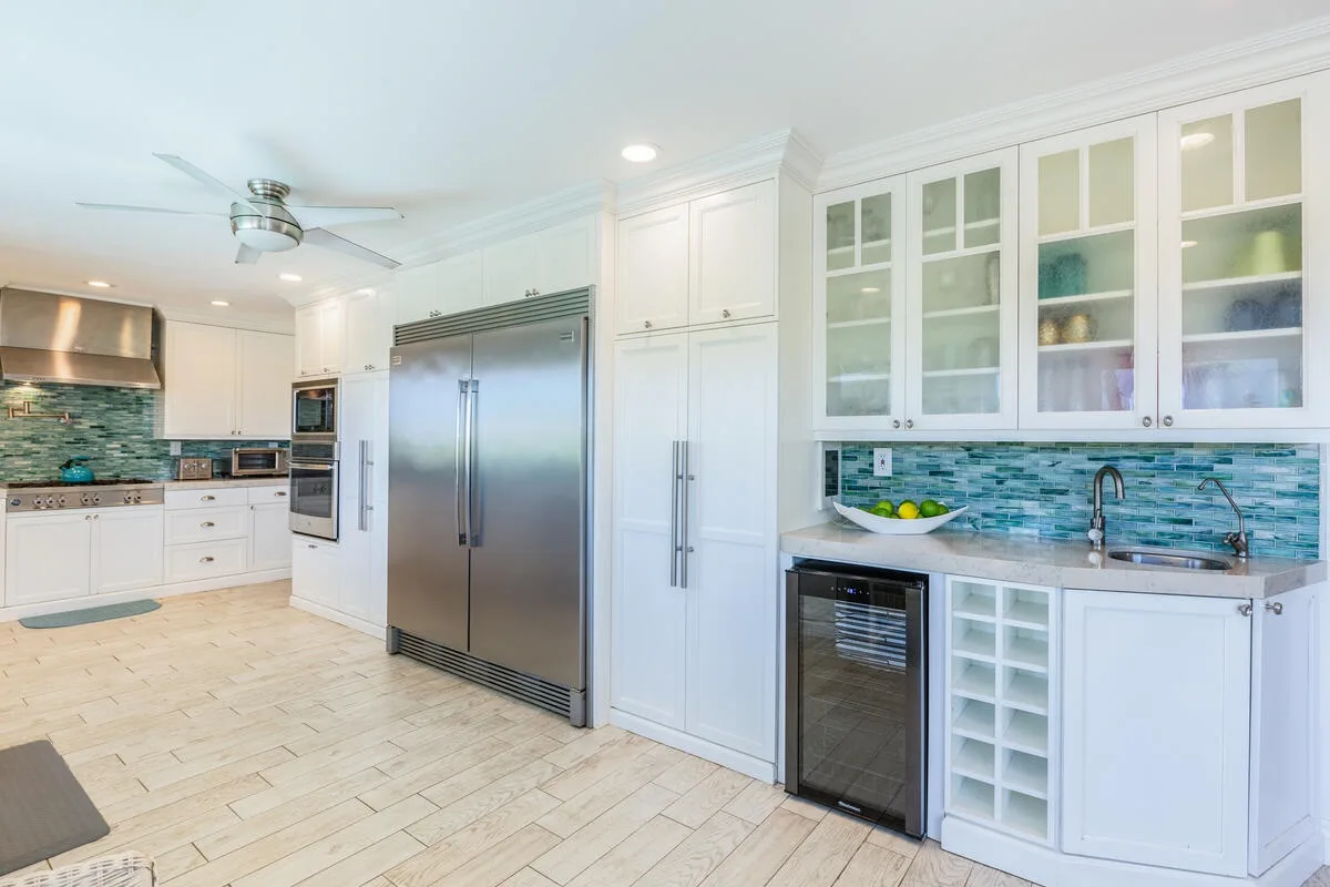 Una cocina luminosa con gabinetes blancos, electrodomésticos de acero inoxidable y un salpicadero de azulejos.