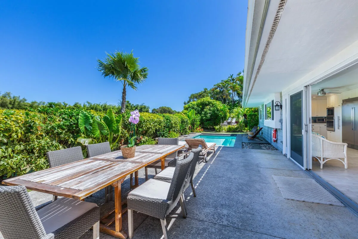 Una zona de comedor al aire libre junto a una piscina y un jardín.
