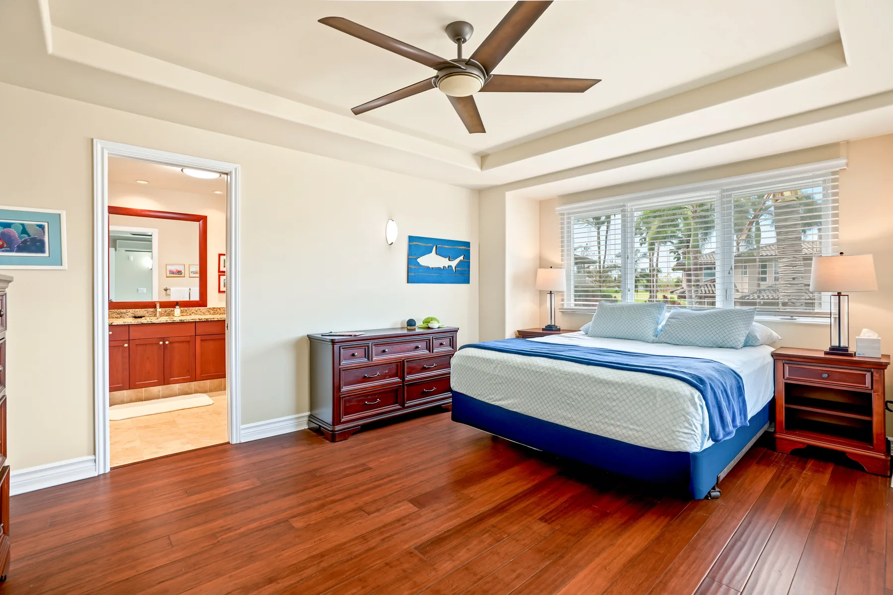 A bedroom with a large bed, bedside tables, and a ceiling fan.