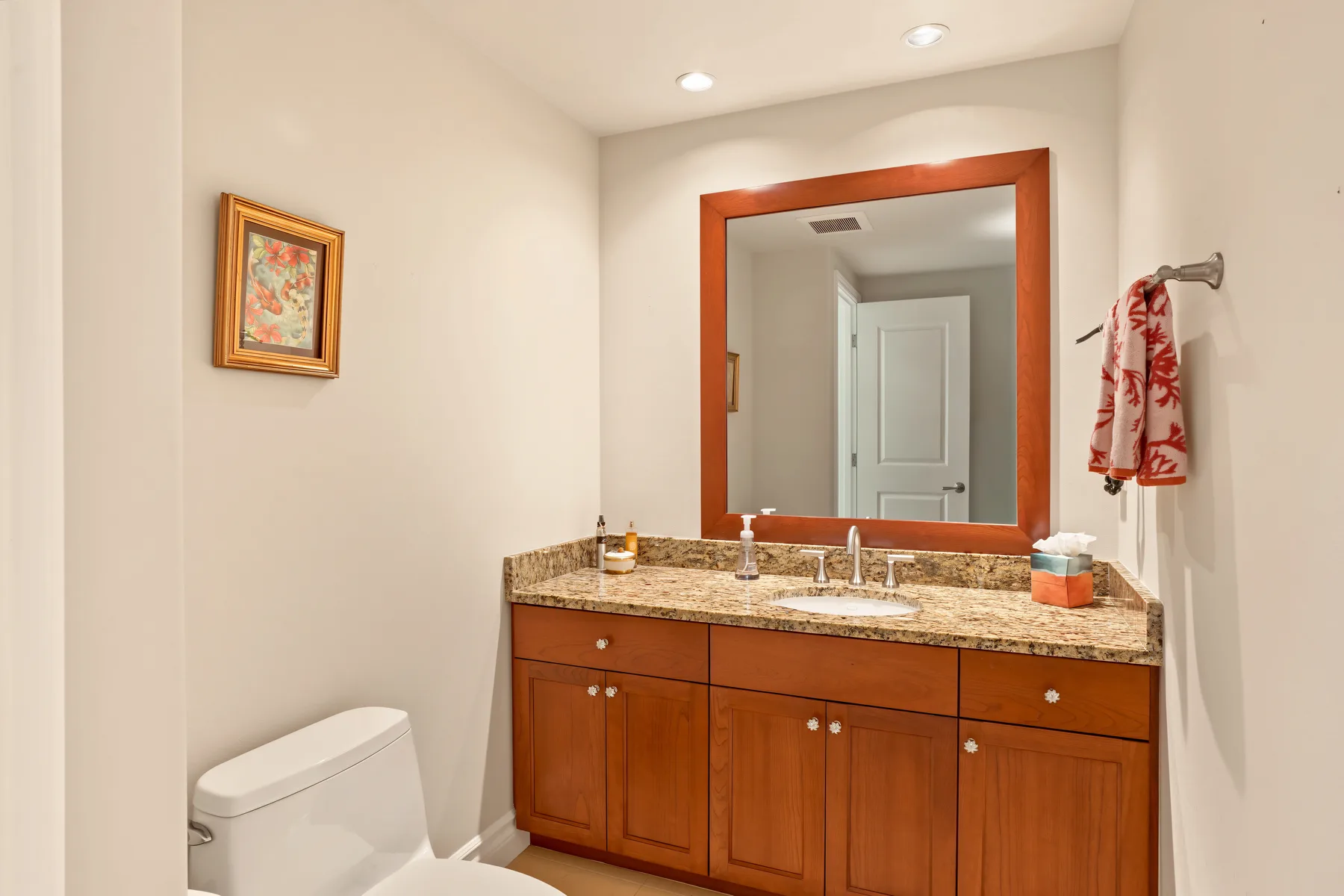 A bathroom vanity with a large mirror, sink, and toilet.
