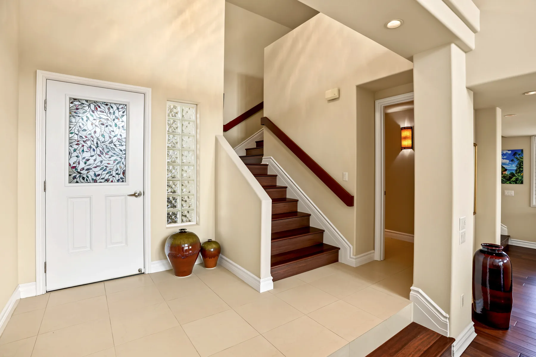 A bright interior entryway with a staircase and a patterned-glass door.