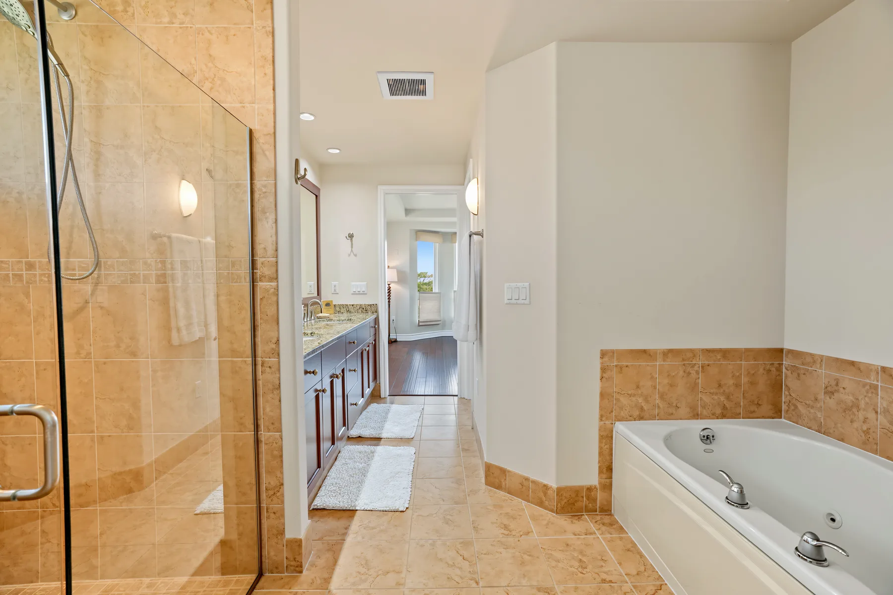 A bathroom with a glass shower, long vanity, and bathtub.