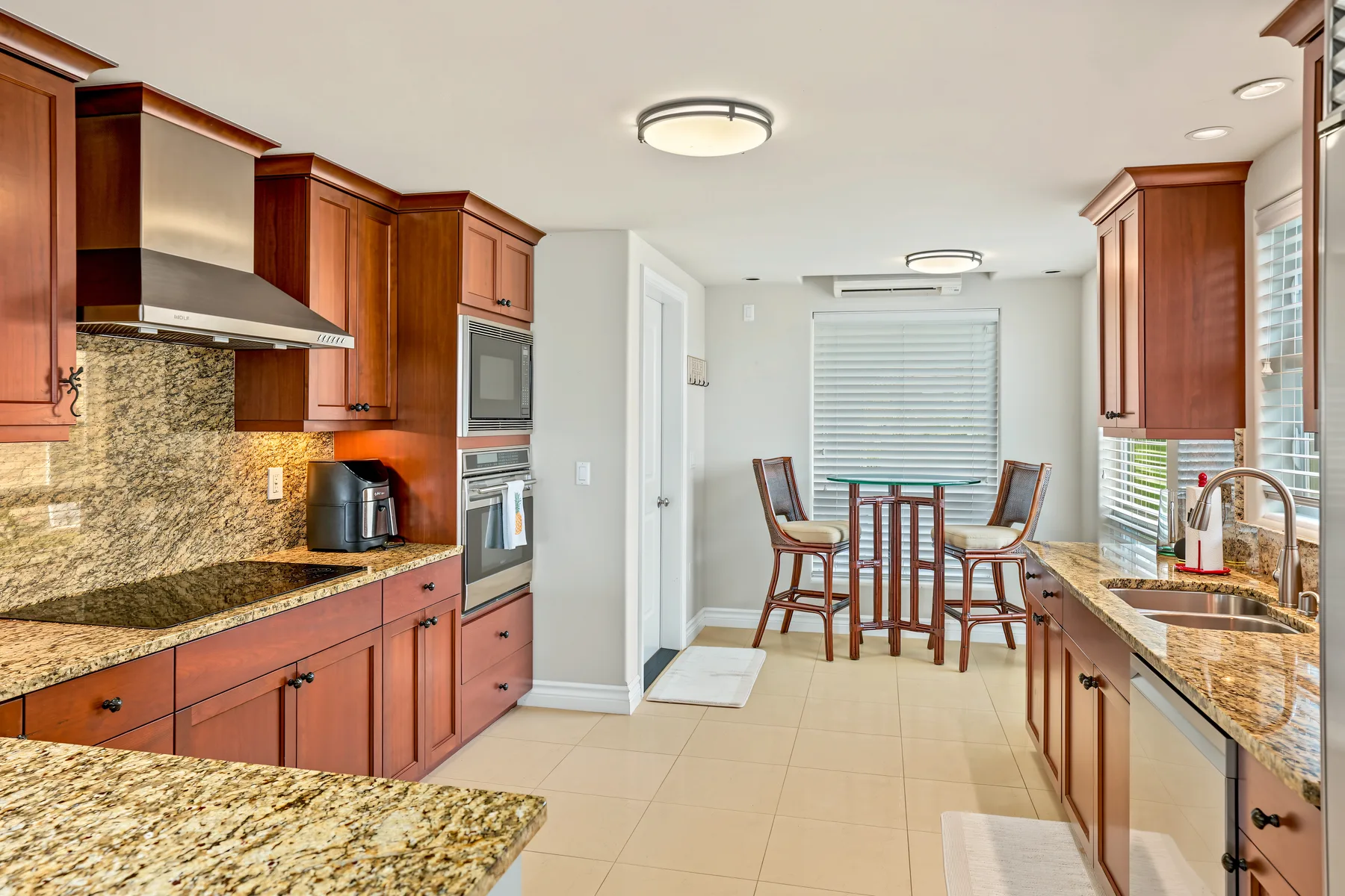 A bright kitchen opens onto a dining area with a table and chairs.