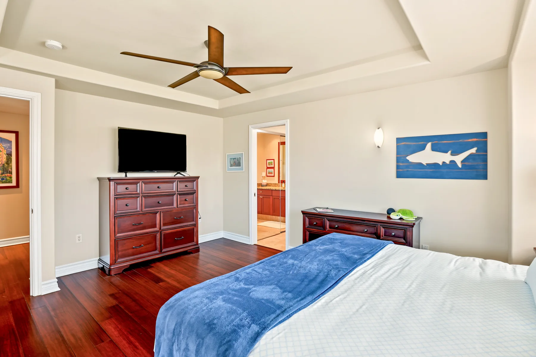 A bedroom with a bed, dark wood furniture, and a ceiling fan.