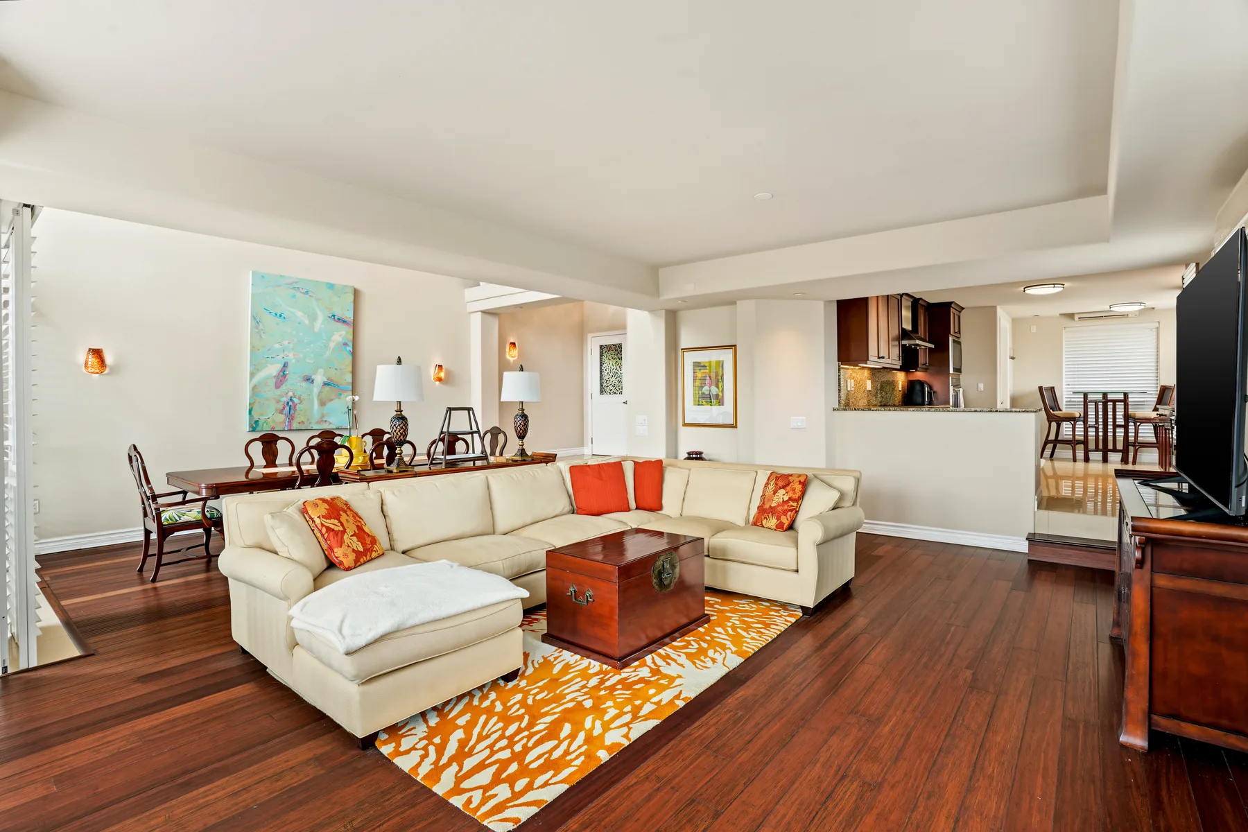 A living room with a sectional seating area and a dining table behind it.