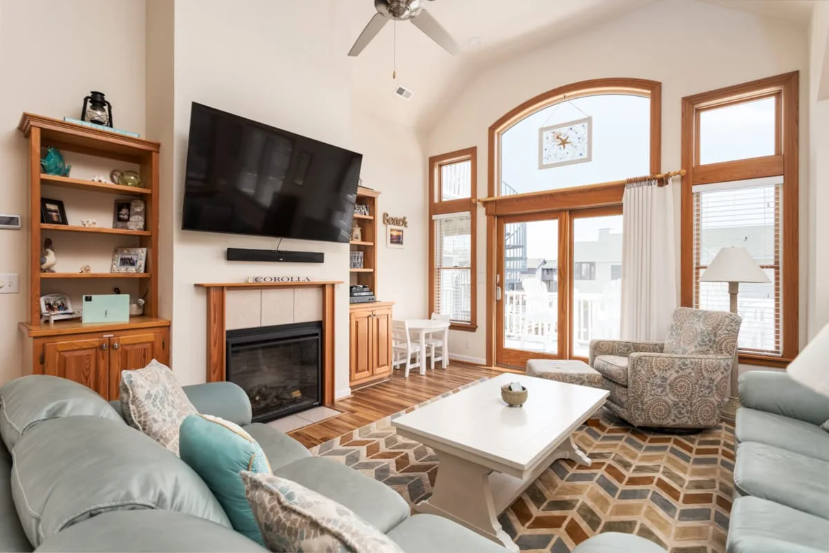 A bright living room with seating around a coffee table and a fireplace.