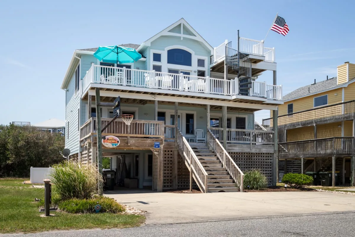 A coastal-style house with raised wooden decks and an exterior staircase.