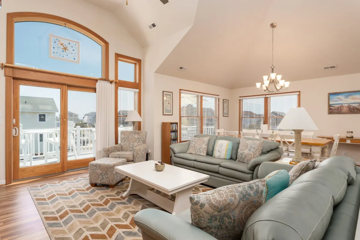 A bright living room with seating, a coffee table, and large windows.