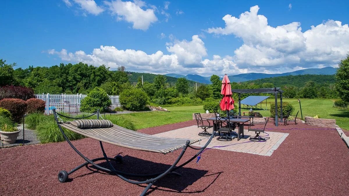 Un patio al aire libre con una hamaca, asientos y vistas de colinas verdes.