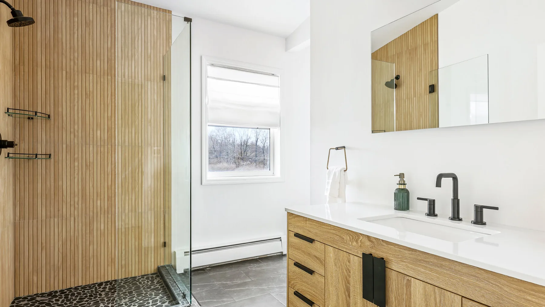 Un baño luminoso con ducha de vidrio, mueble de madera y ventana.