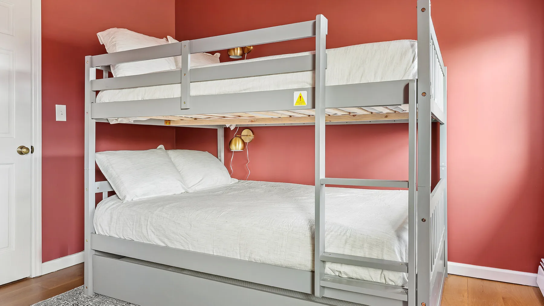Una litera con ropa de cama blanca está junto a paredes color coral.
