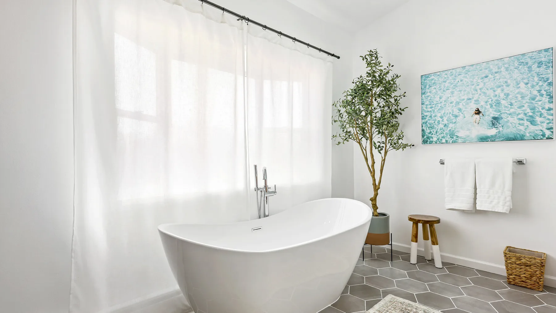 Un baño luminoso con una bañera exenta y una ventana amplia.
