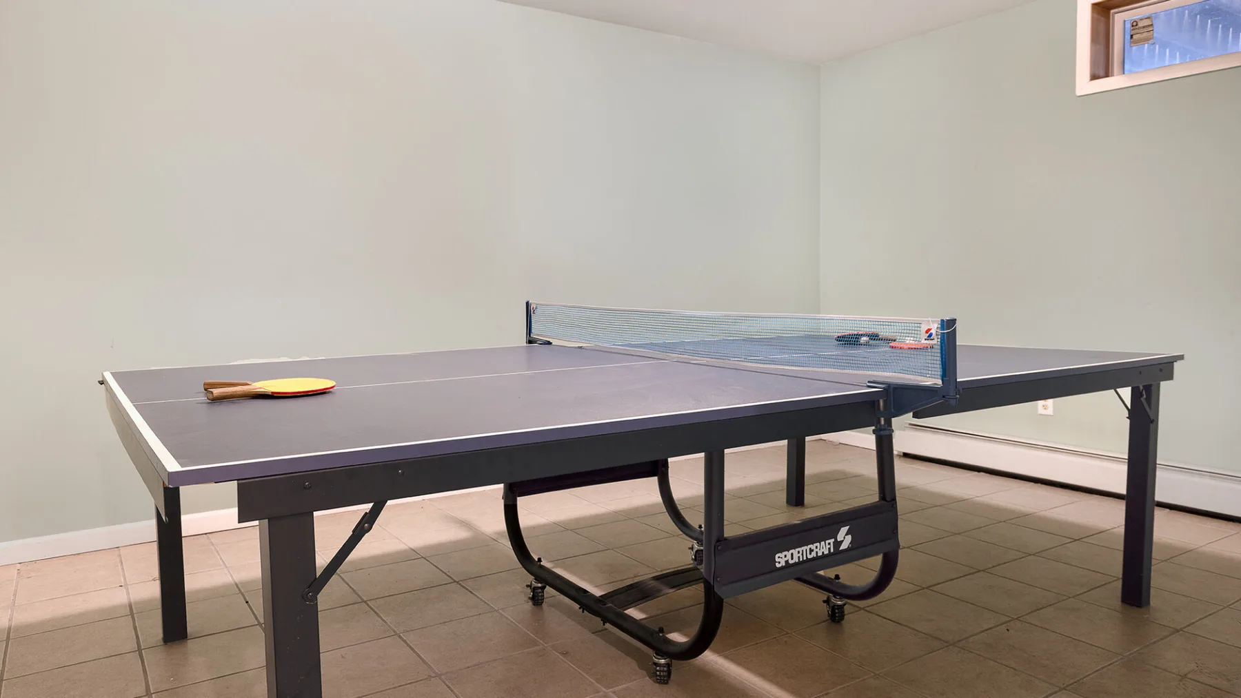 Una mesa de ping-pong está en una sencilla sala de recreación interior.