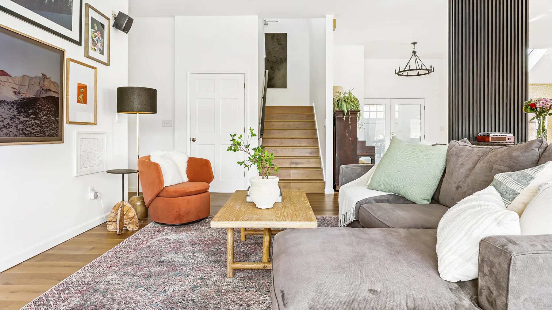 Una sala luminosa tiene una zona de asientos, una mesa de centro y una escalera.