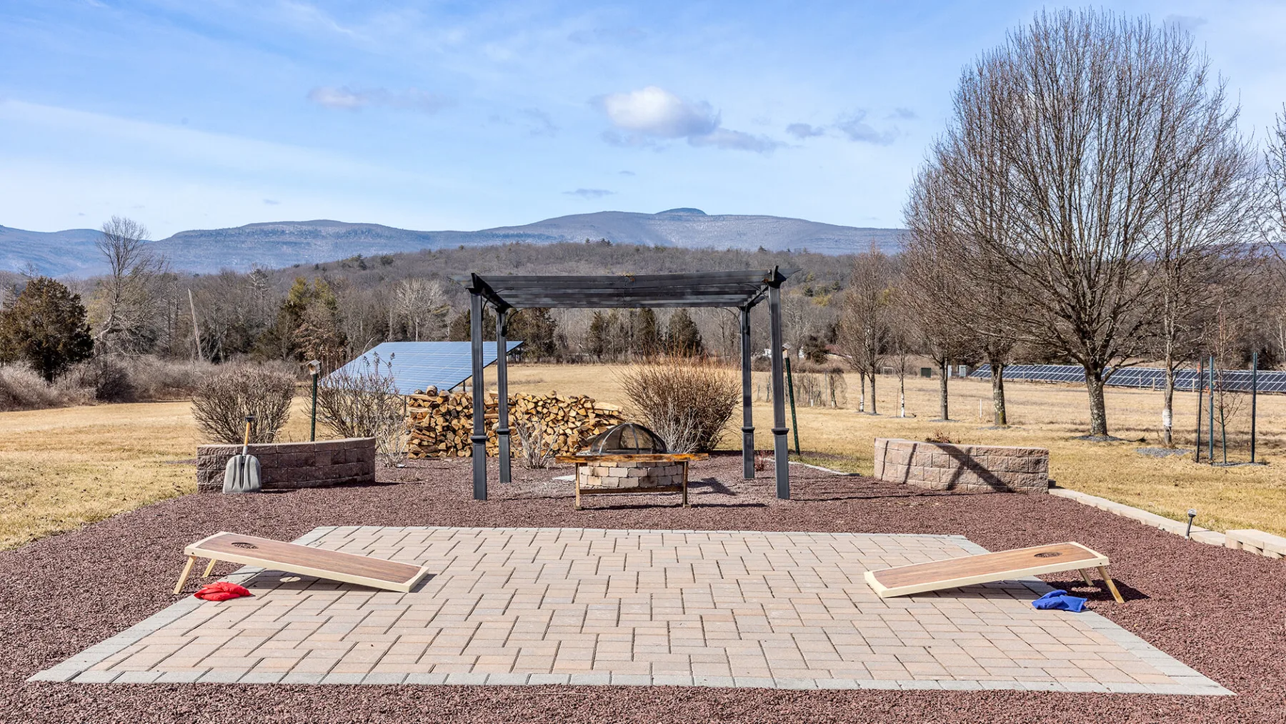 Un patio al aire libre con pérgola, asientos y vistas a las montañas.
