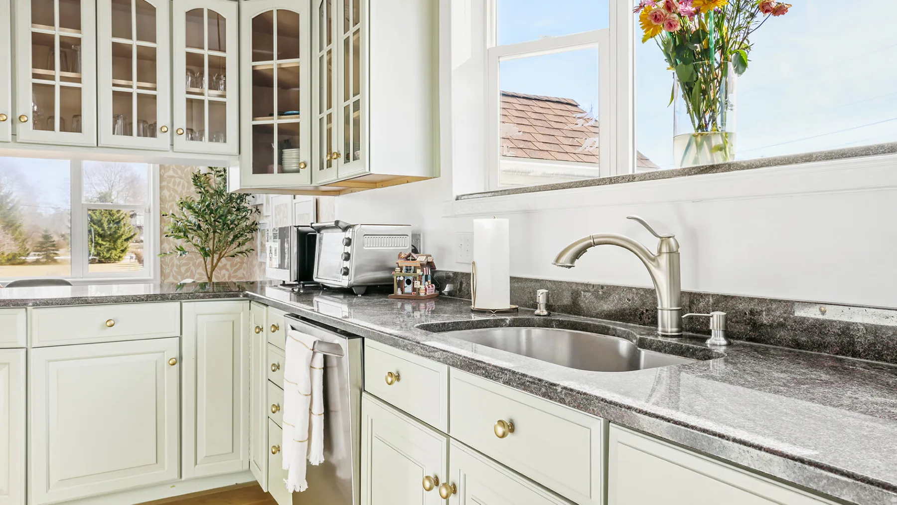Una cocina luminosa con gabinetes claros, una encimera y un fregadero bajo la ventana.