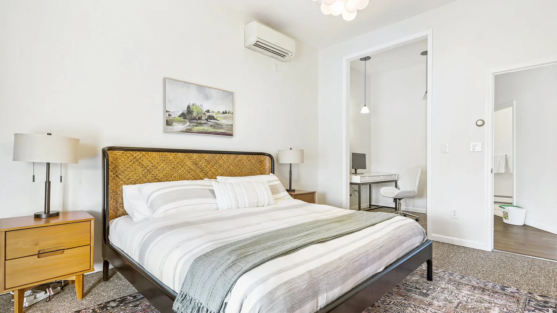 Un dormitorio luminoso con una cama tendida y mesitas de noche.