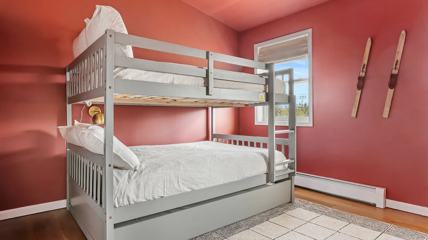 Una litera con ropa de cama blanca está en un dormitorio de paredes coral.