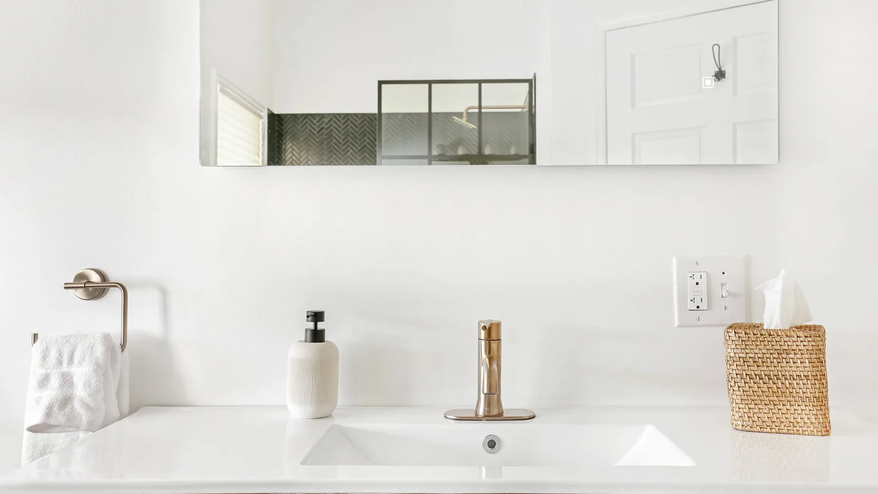 Un lavabo de baño con grifo de pared y artículos de aseo sobre la encimera.