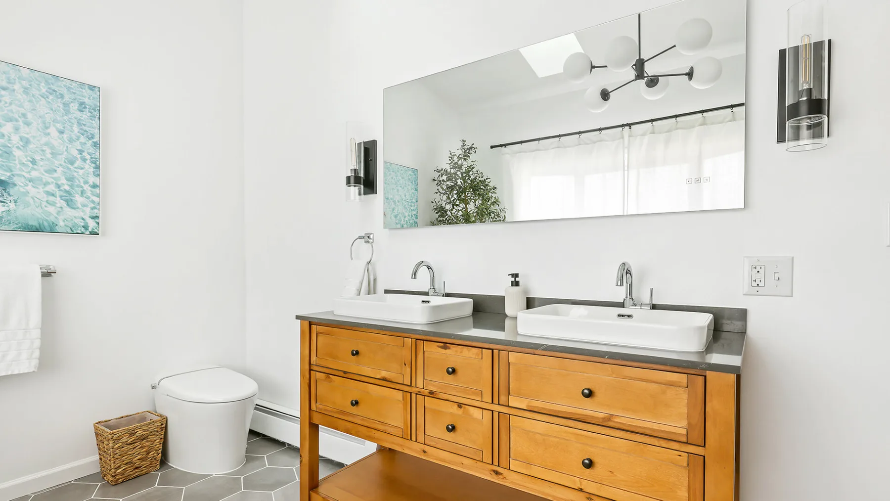 Un baño luminoso con un mueble de lavabo doble de madera y un espejo amplio.