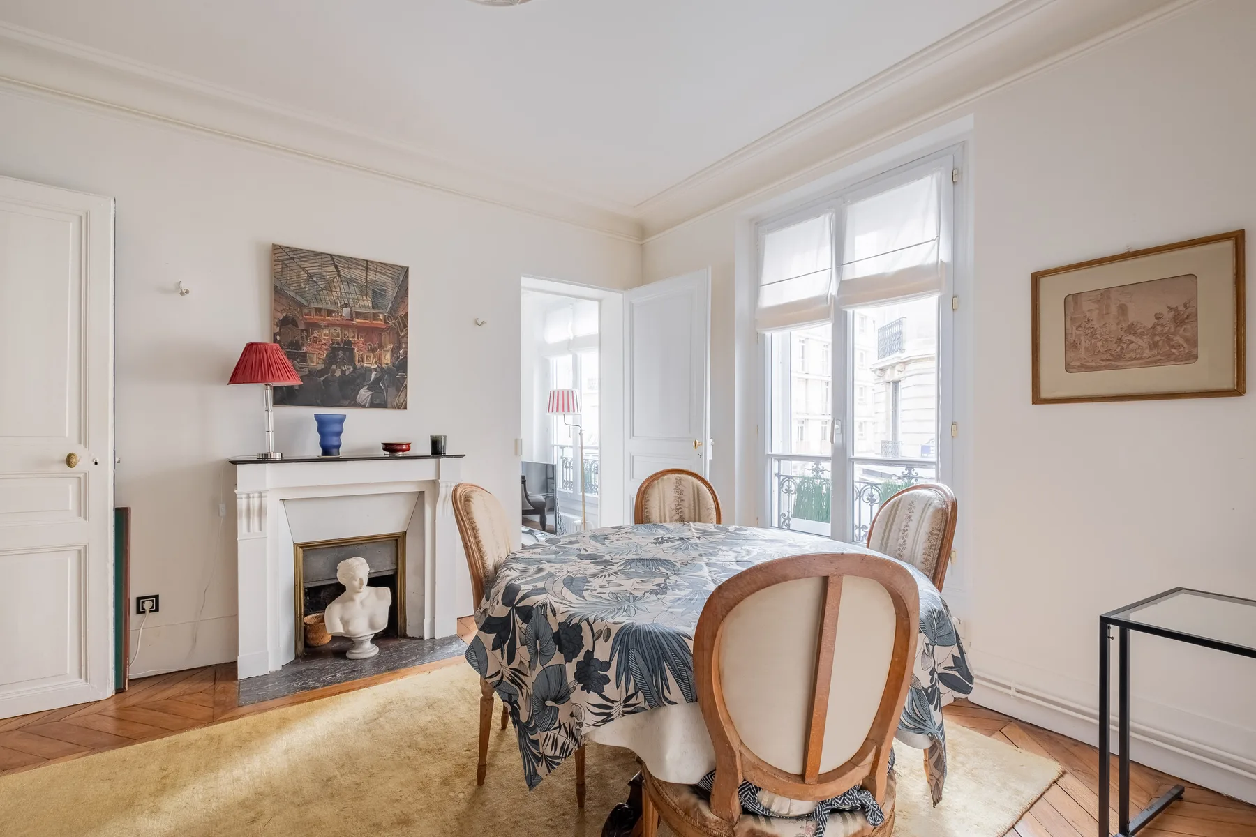 Un comedor luminoso con una mesa junto a ventanas altas y una chimenea.