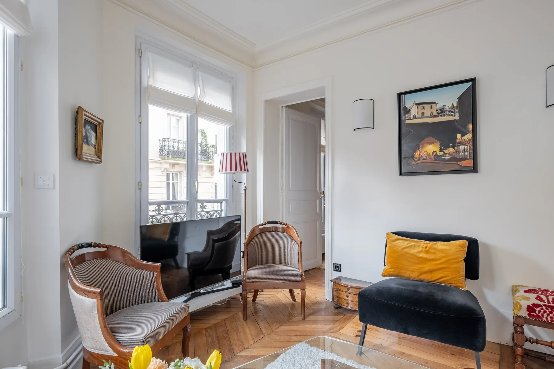 Una sala luminosa con asientos junto a grandes ventanas y un cuadro enmarcado.