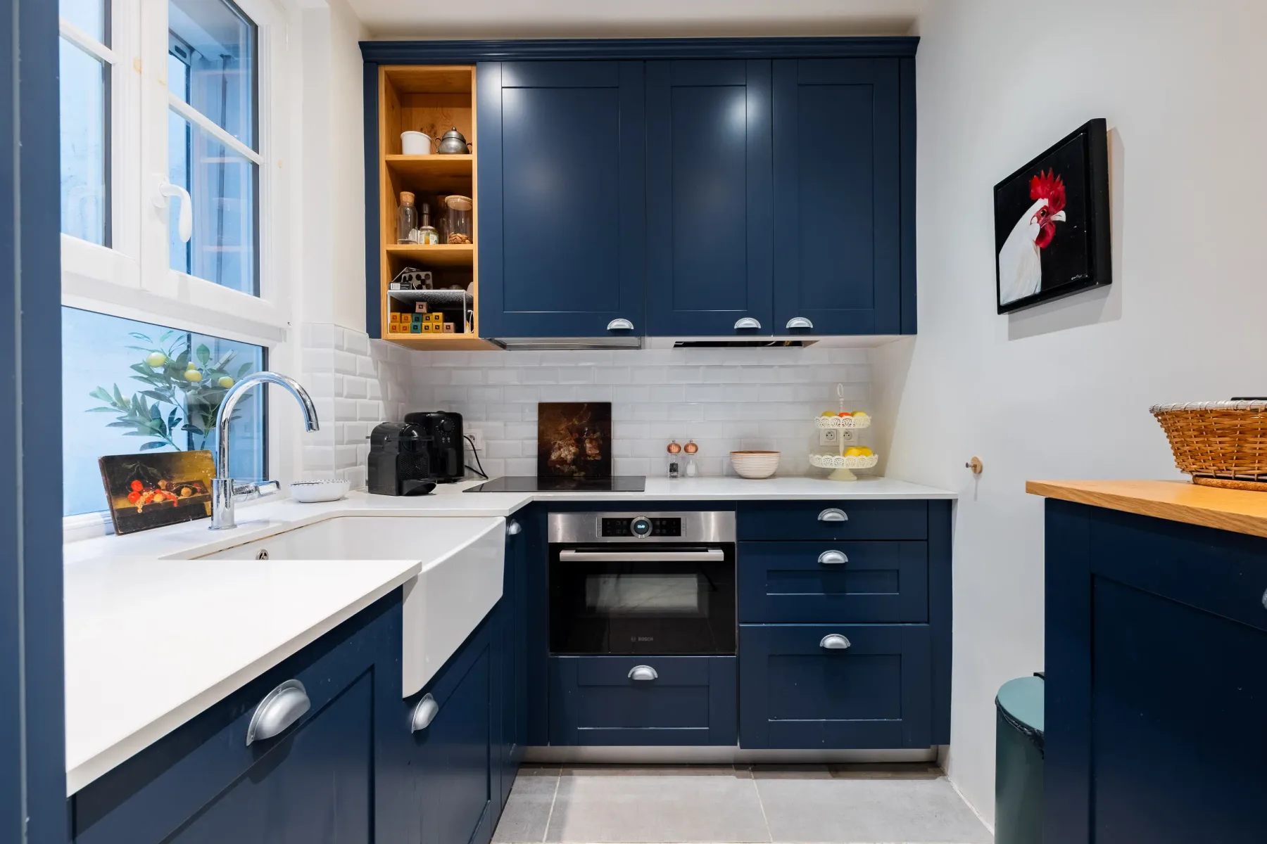A compact kitchen with dark blue cabinets, white counters, and an oven.
