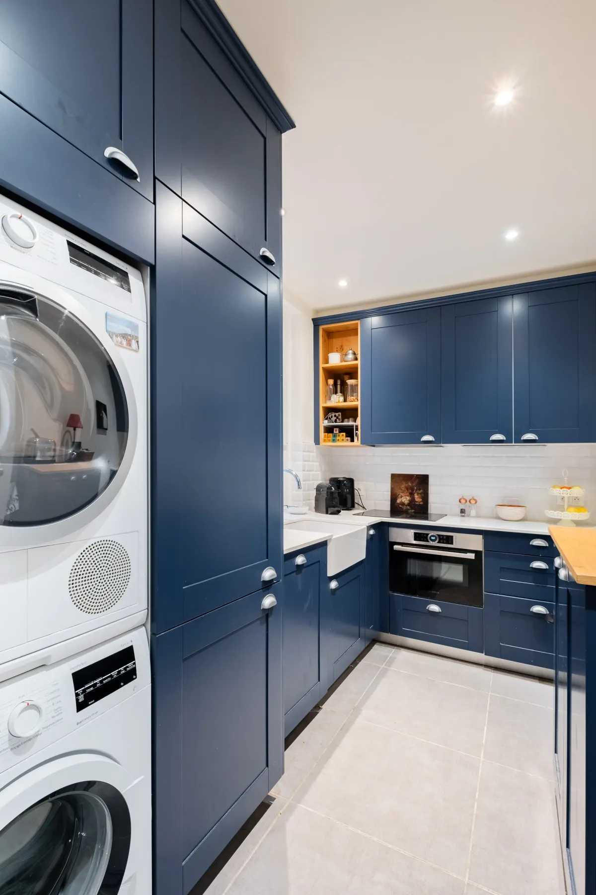 A blue kitchen with built-in appliances and a washer and dryer.