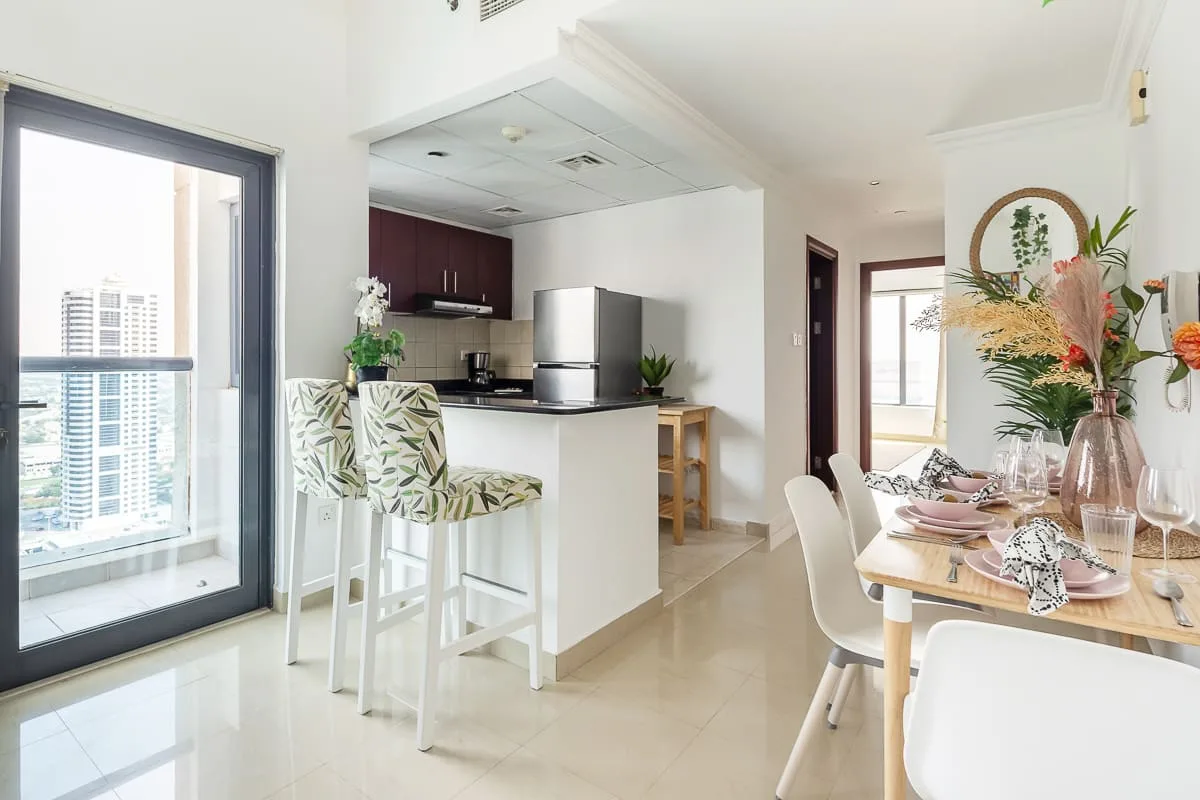 Un comedor luminoso de planta abierta con cocina y una mesa junto a la ventana.