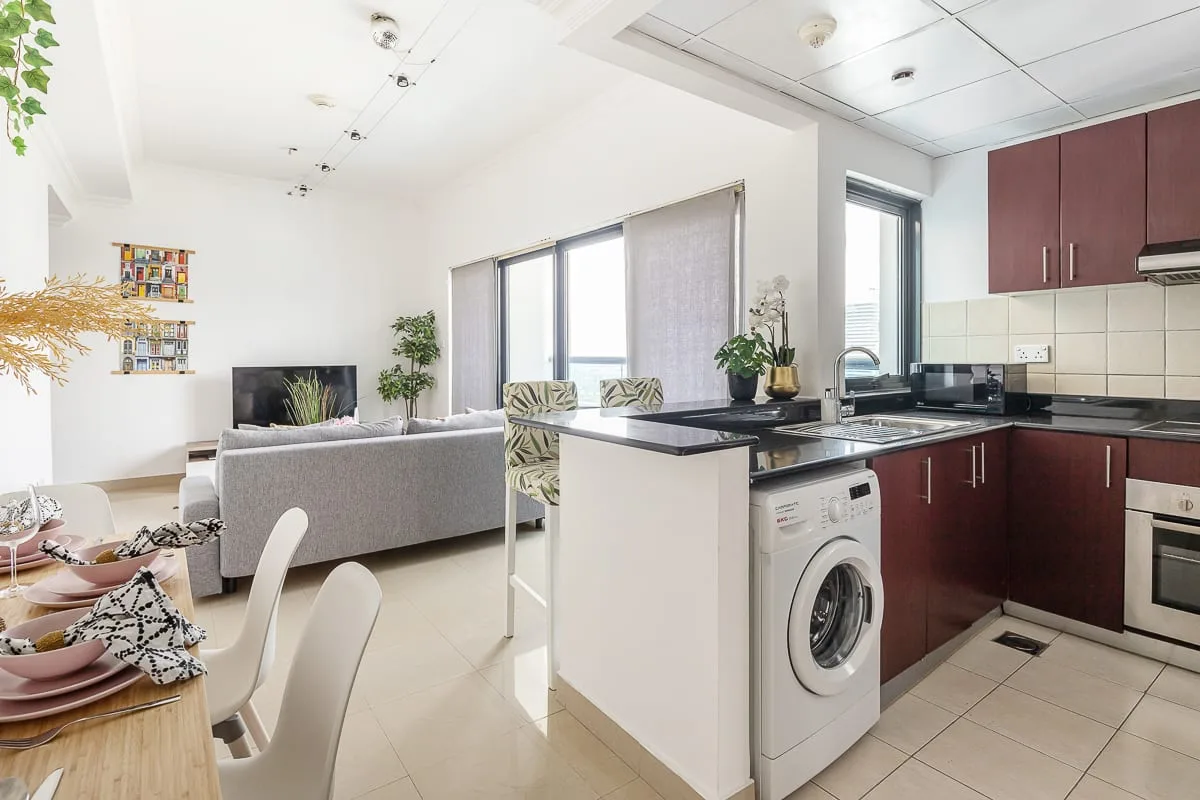 Sala de estar y cocina de concepto abierto, con una barra y una lavadora.