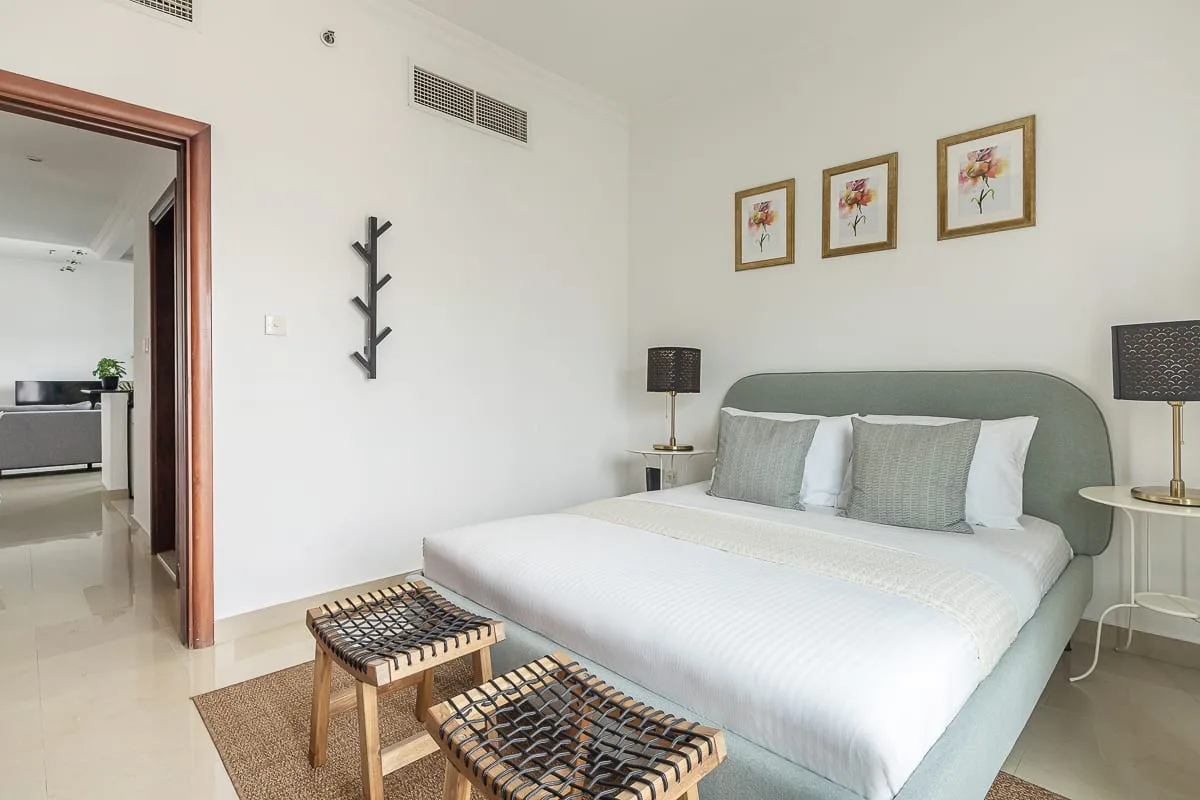 Dormitorio con una cama grande, mesitas de noche y cuadros florales enmarcados.