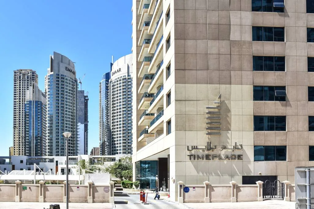 Una calle con edificios altos, incluida una torre con un letrero visible.