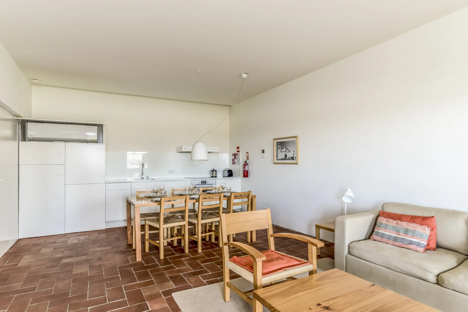 A bright dining and living area with a wooden table and seating.