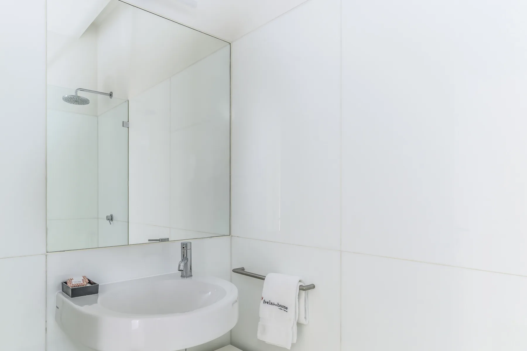 A bright bathroom with a sink, mirror, and shower.