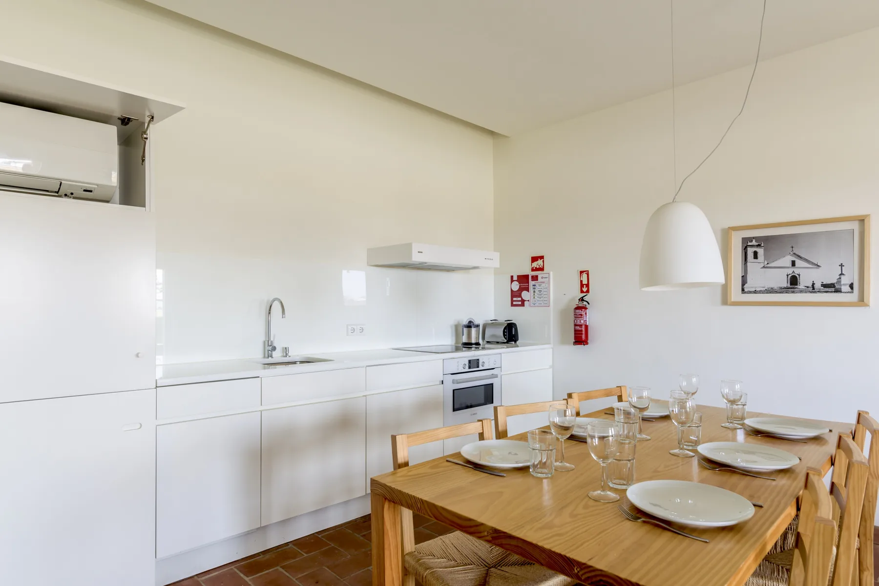 A bright kitchen and dining area with white cabinets and a wooden table.