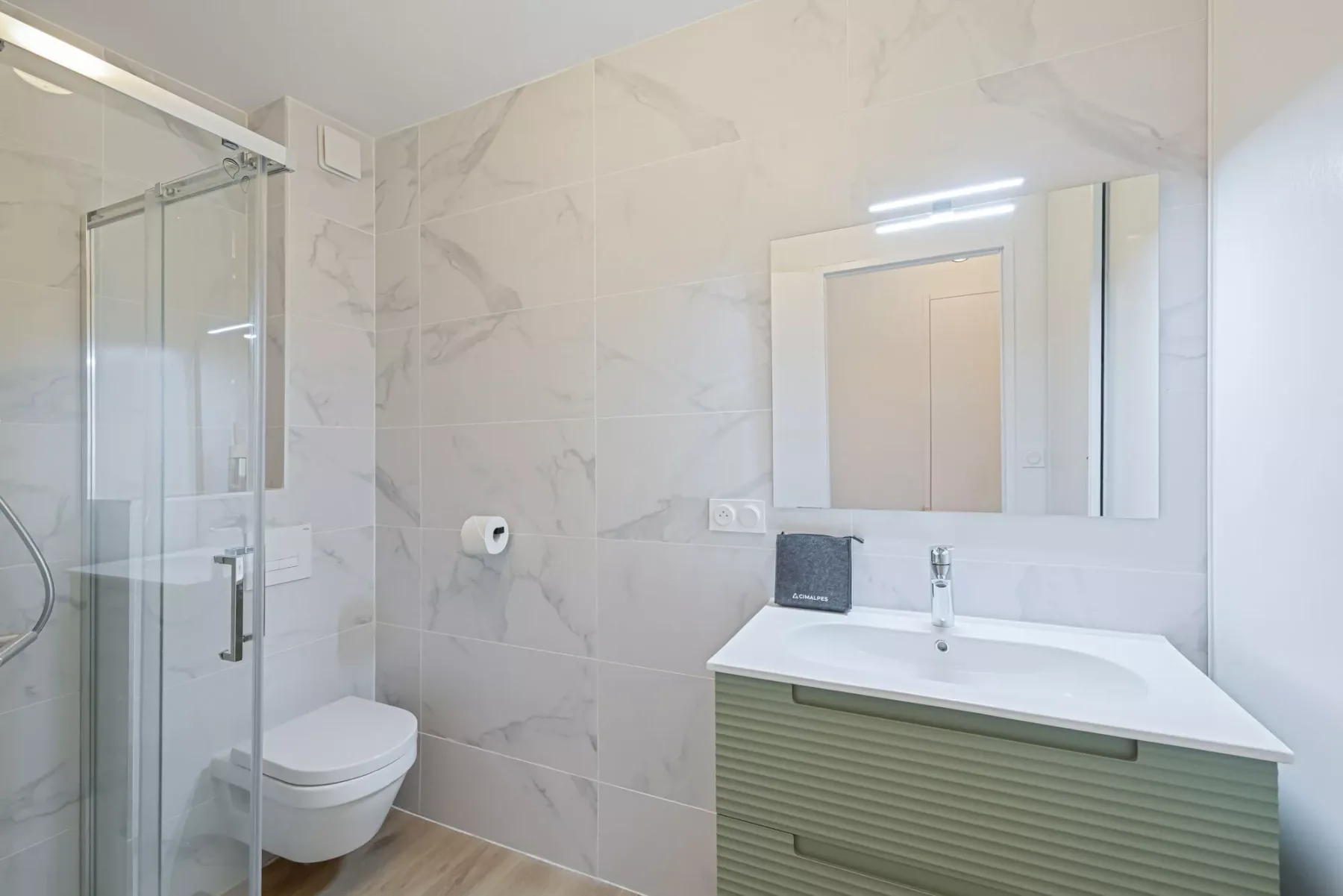 A bright bathroom with a glass shower, toilet, and vanity.