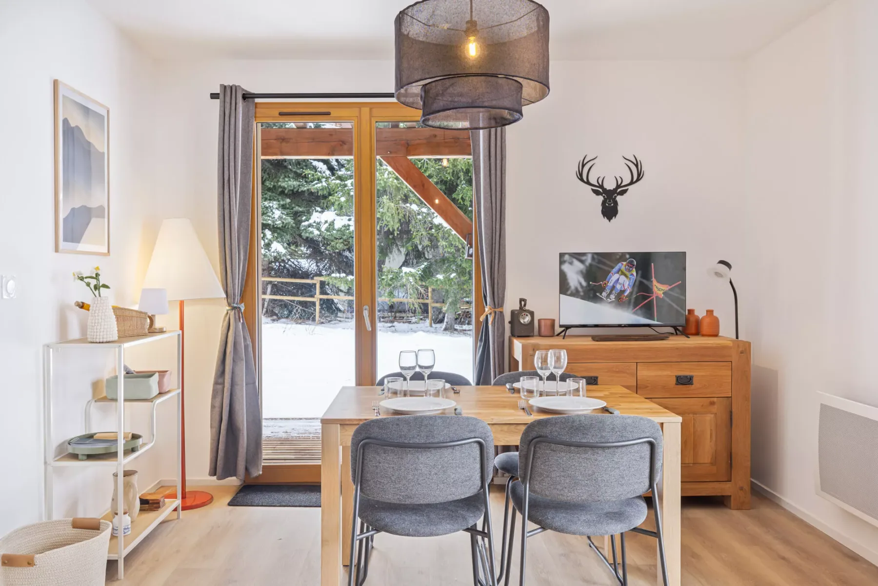 Comedor con una mesa de madera y sillas junto a una gran puerta de vidrio.