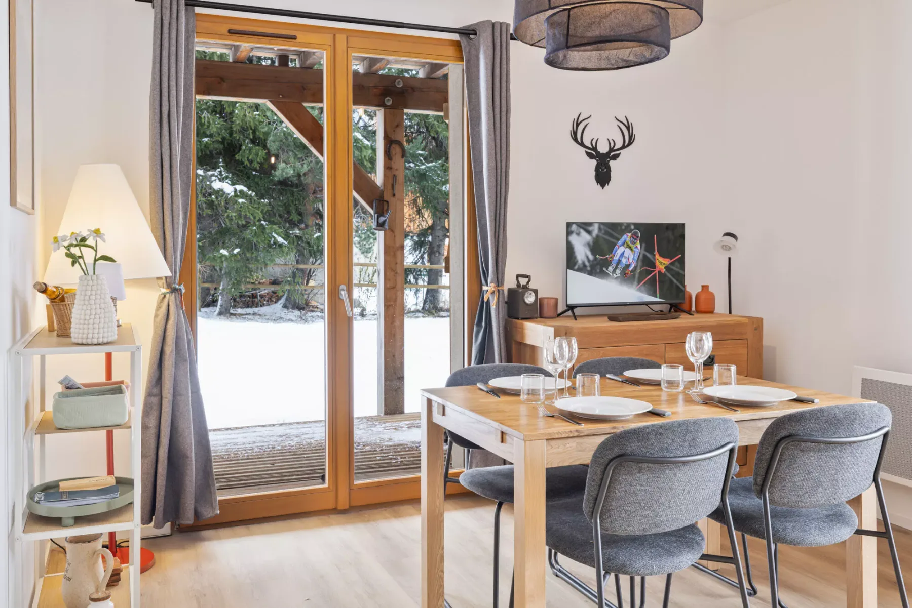 A dining area with a wooden table and large glass doors overlooking a snowy garden.