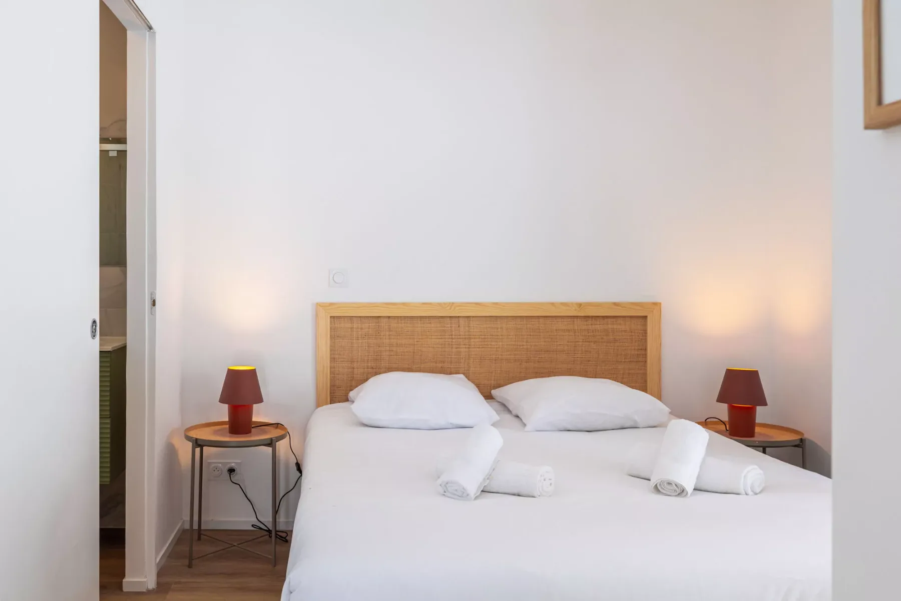 A bright bedroom with a neatly made bed and matching bedside lamps.