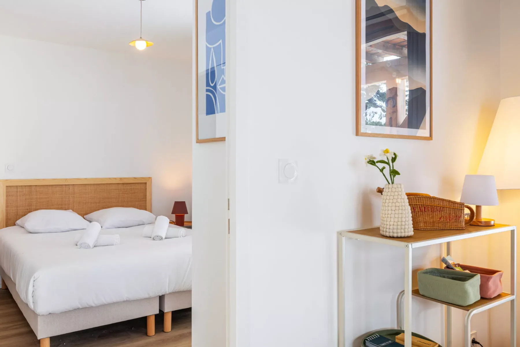 A bright bedroom with a neatly made bed and a small console table.