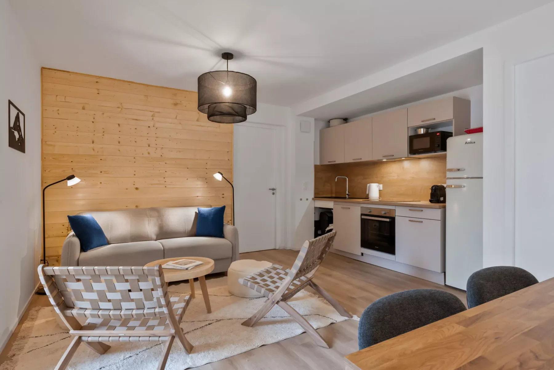 Una sala de estar con asientos y una cocina abierta.