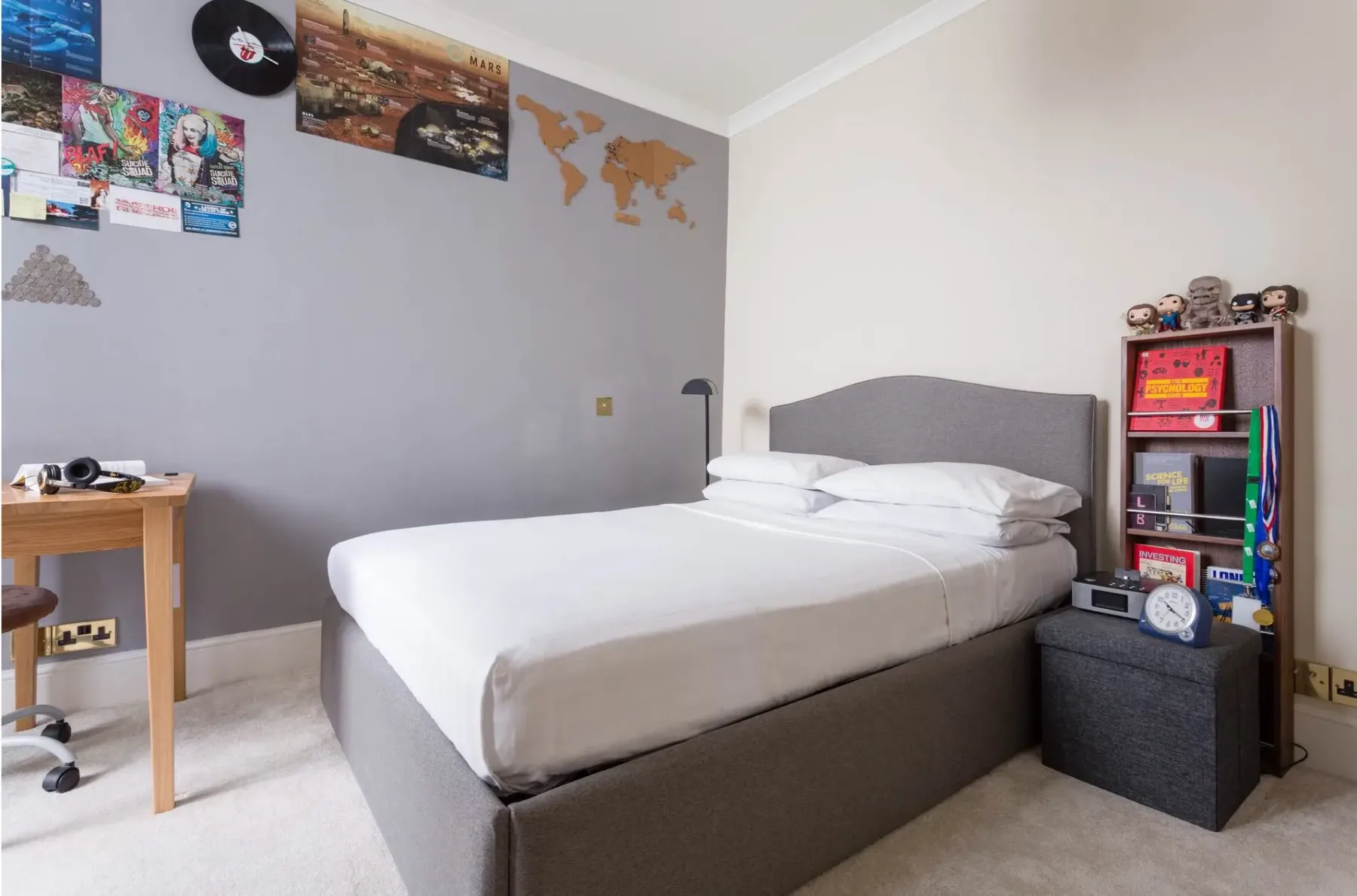 Dormitorio con una cama bien tendida y coloridos adornos en la pared.