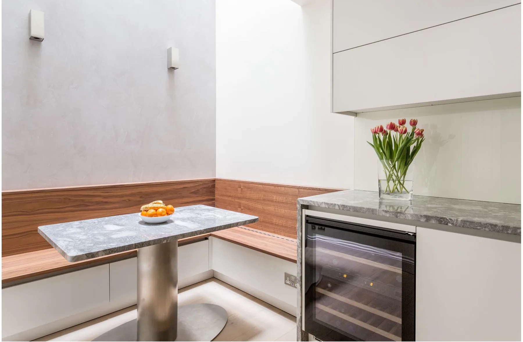 A modern kitchen with a small table and a built-in wine refrigerator.