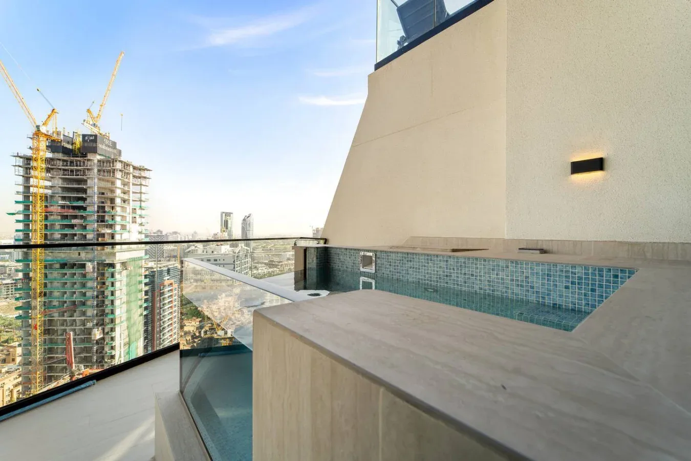 Una terraza en la azotea con una bañera de hidromasaje integrada y vistas a una construcción cercana.