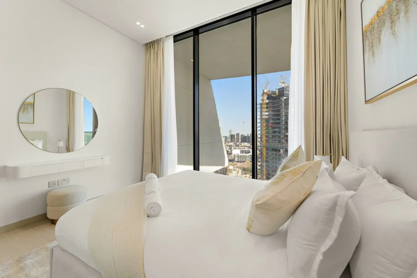 Un dormitorio luminoso con una cama blanca junto a ventanales.