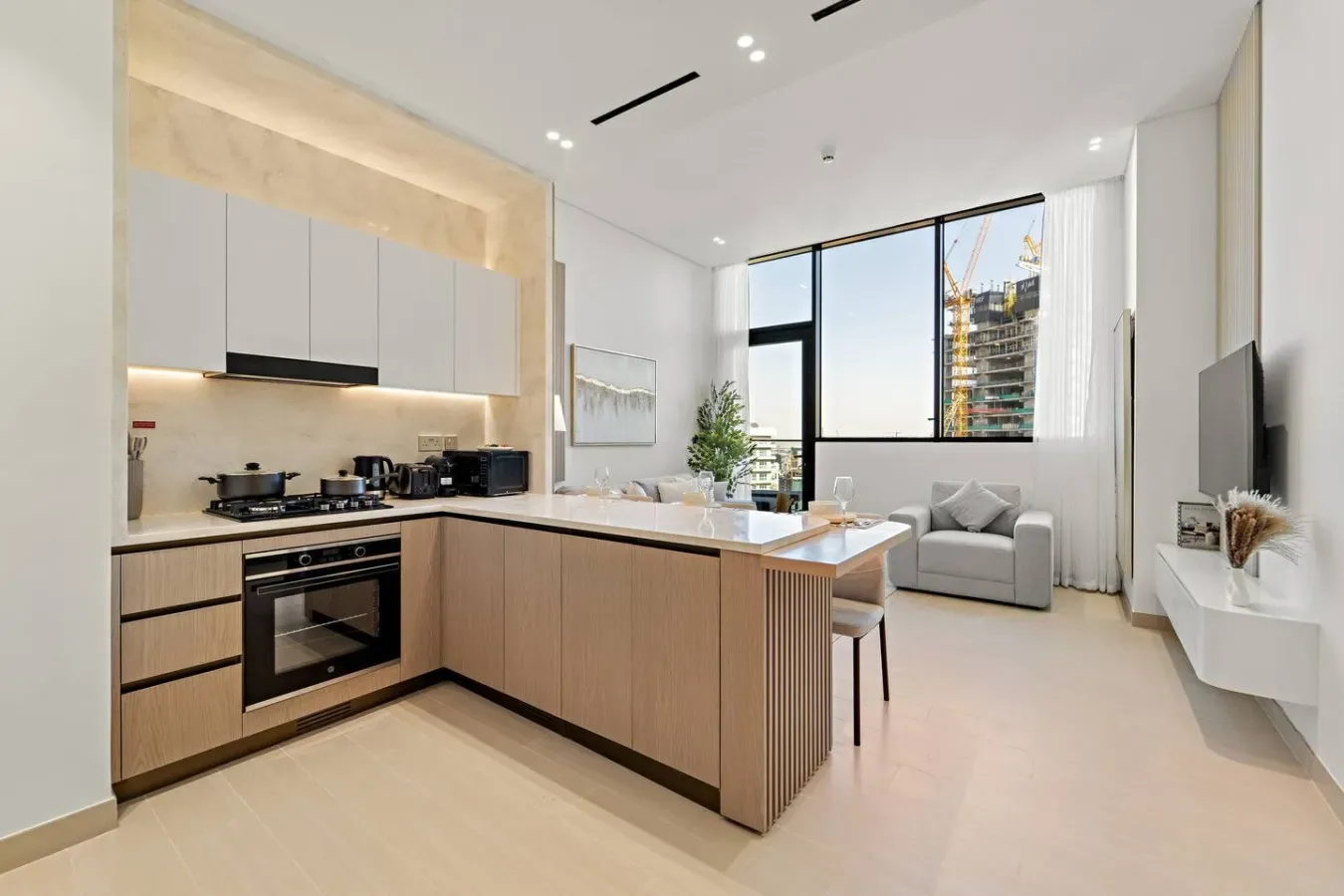 Una cocina moderna y luminosa se abre a una sala de estar con grandes ventanales.