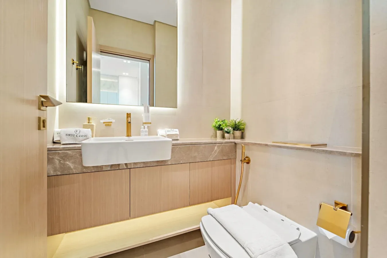 Un baño moderno con un amplio lavabo, espejo de pared e inodoro.