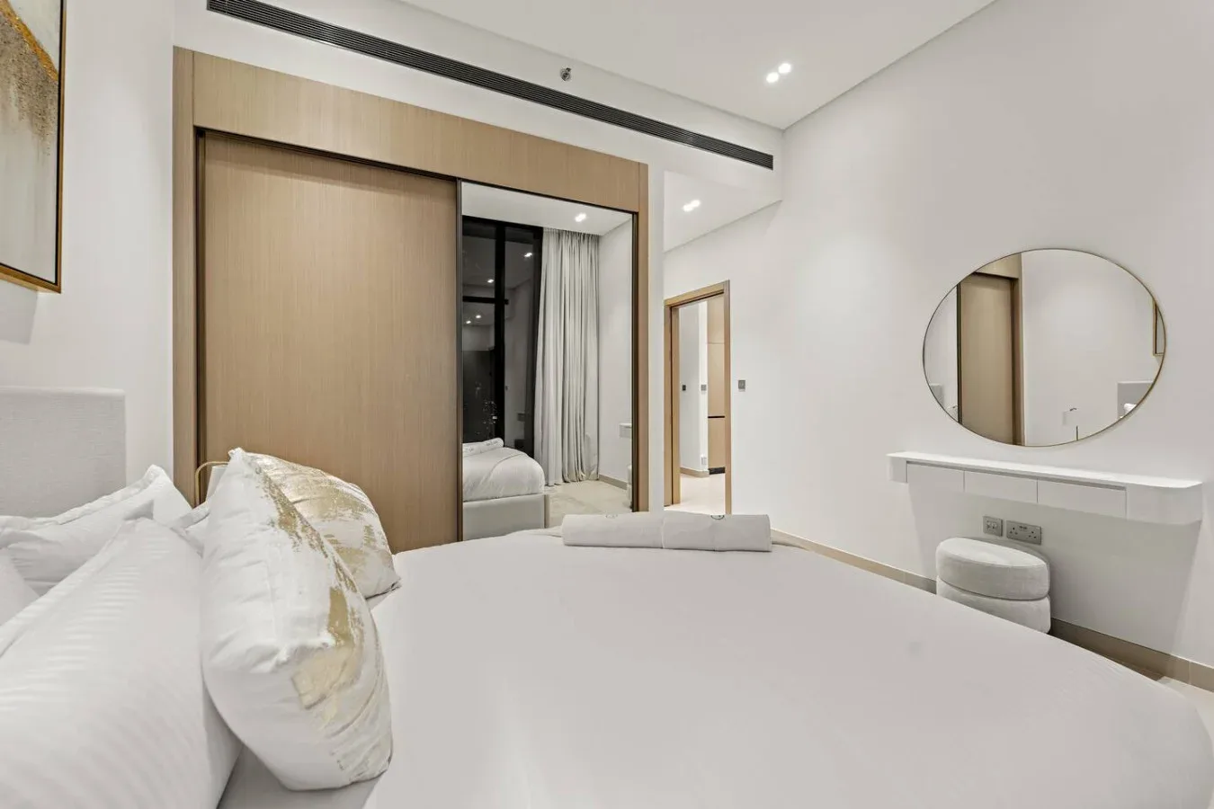 Un dormitorio con cama, armario con espejo y tocador.